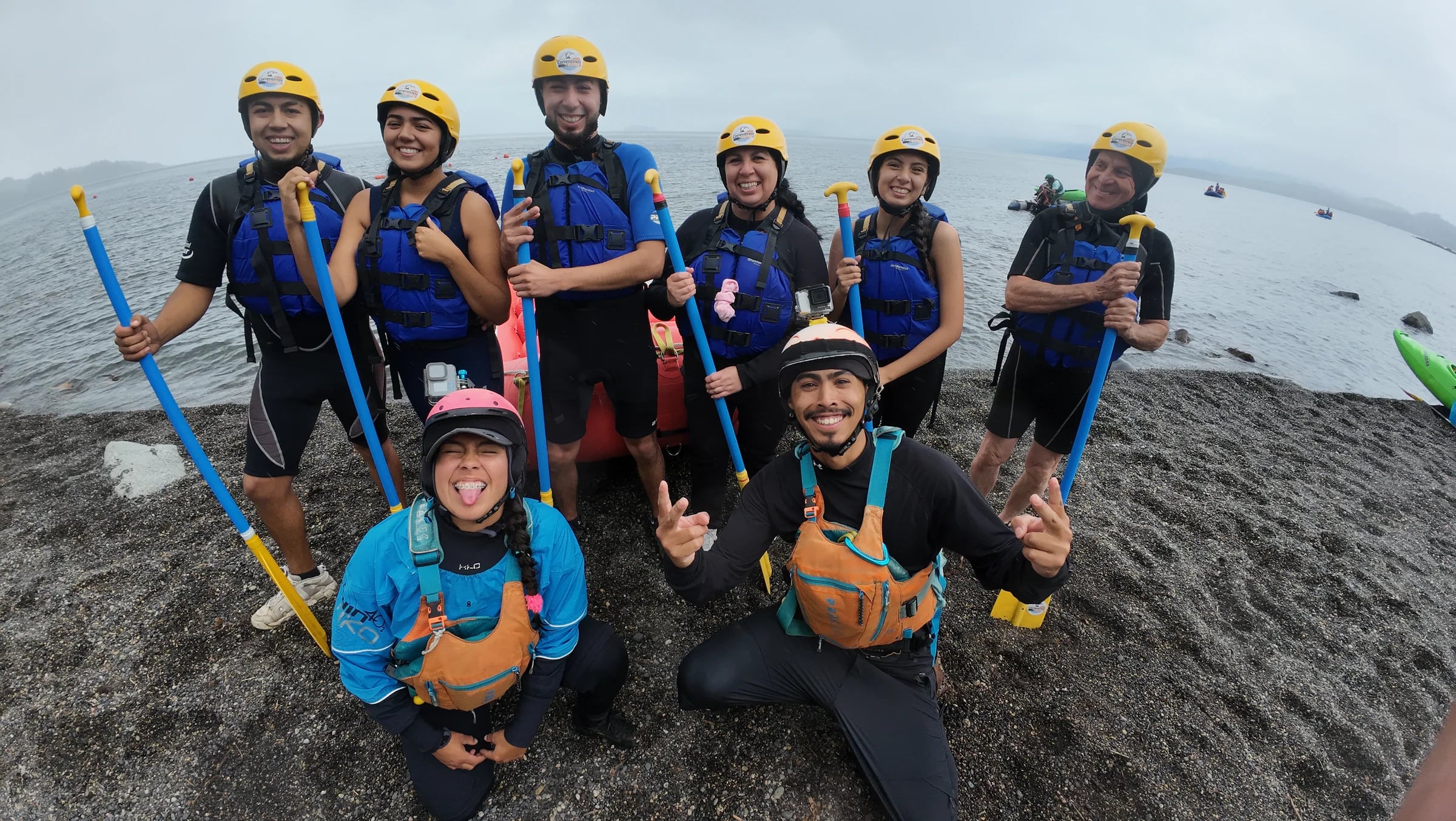 Grupo grande posando con sus remos en la orilla del lago
